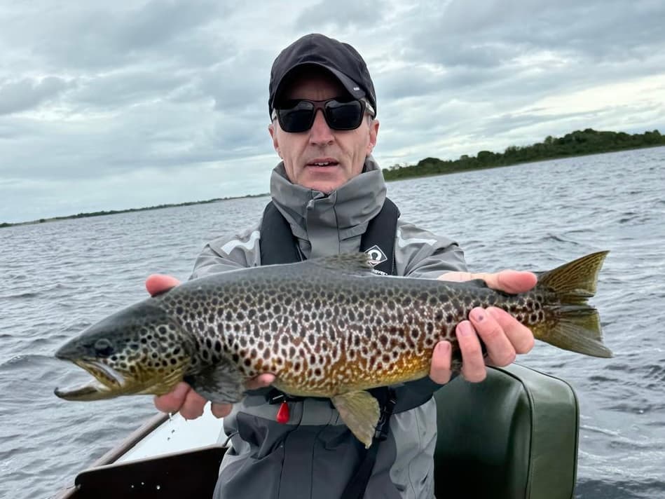 Angler holding a wild Irish brown trout on a lough boat
