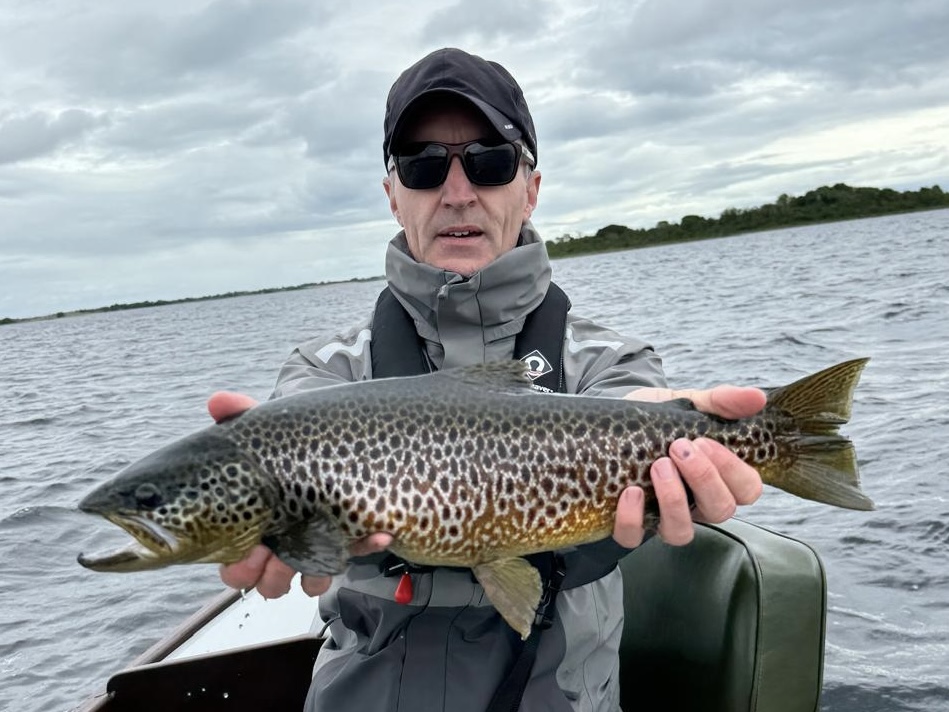 Angler holding a wild Irish brown trout on a lough boat